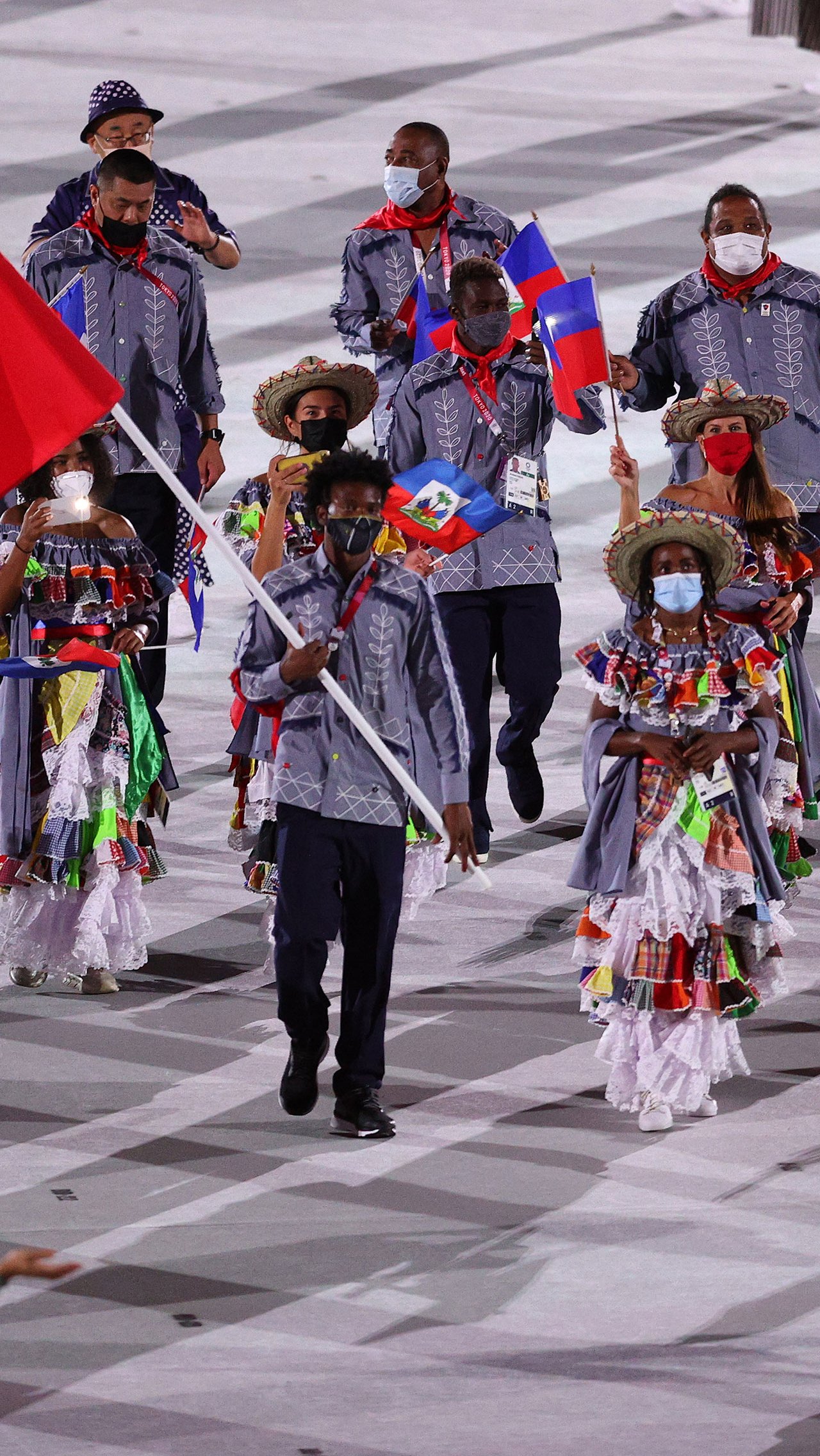 В экзотических костюмах пришли спортсмены из сборной Гаити. Девушки были одеты в цветастые сарафаны и яркие панамы, а мужчины — в синие рубашки с национальным узором.